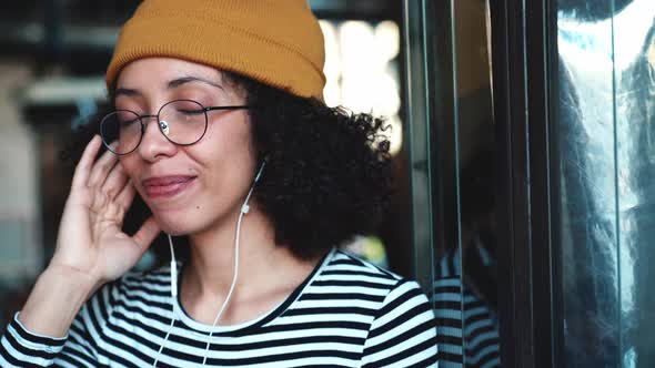 Positive woman wearing hat listening music in headphones