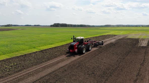 Red Harvester Drives Across Field and Plows Earth