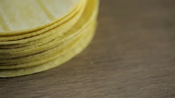 Fresh yellow corn tortillas on a wood background.