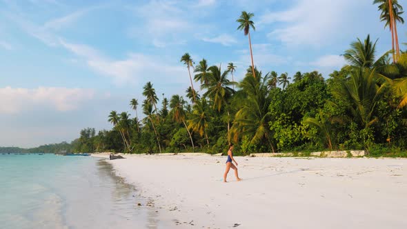 Woman walking on white sand beach turquoise water tropical coastline Pasir Panja