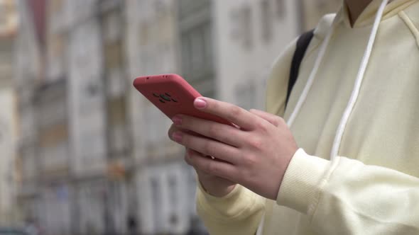 Closeup view on hands with mobile phone on city street