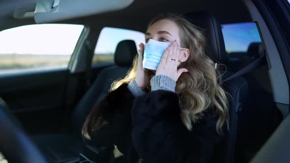 Beautiful Woman Adjusting Covid19 Face Mask Sitting on Driver's Seat in Car