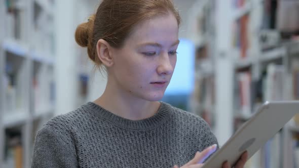 Redhead Woman Browsing Internet on Tablet at Work