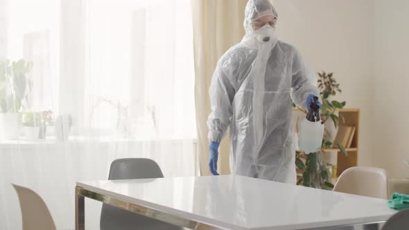 Woman in Disposable Protective Suit Disinfecting Surface at Home
