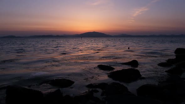 Sea Waves on a Background of a Red Sunset and Mountains