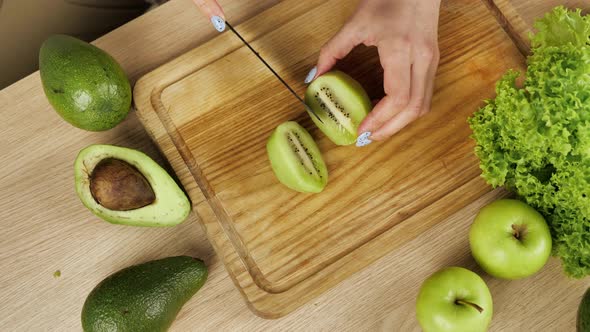 The Cook Cuts Pieces of a Kiwi