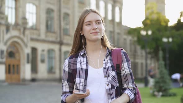 Young Attractive Woman Walking in The Park and Listening Music in The Headphones