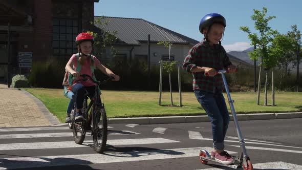 Group of kids riding bicycles and scooter and crossing the road