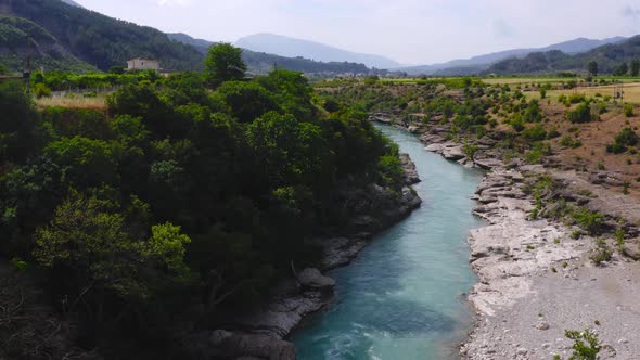 Stunning drone view of fresh waters of Vjosa river amidst beautiful green cliffs and mountains. Aeri