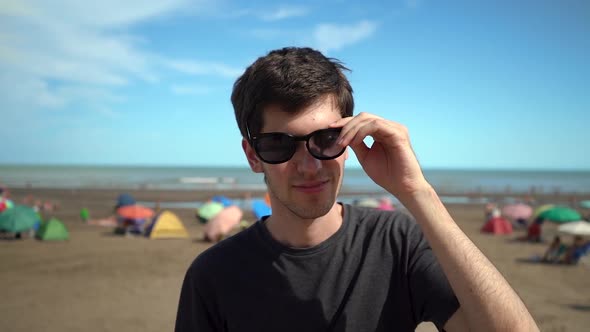 Young Handsome Man Put On Black Sunglasses Then Smile At Camera. - close up, slow motion