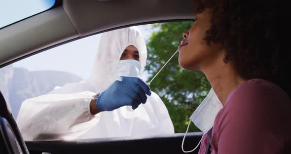African american woman, having covid test done while sitting in car by medical worker outdoors