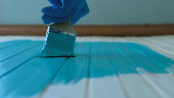 Painter Drives Brush Along a Clean Wooden Board with Turquoise Paint in Slow Motion