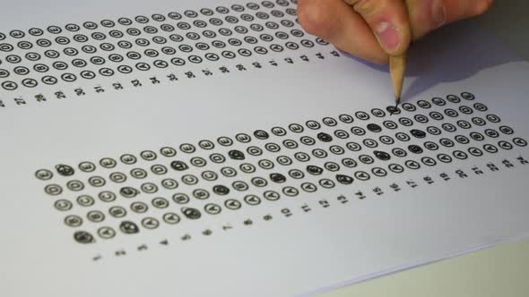 Male student hand testing doing examination test with anger. Standardized test form and answers bubb