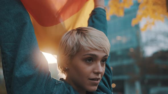 Beutiful Young Woman with Short Hair Waving Rainbow Flag in the Park