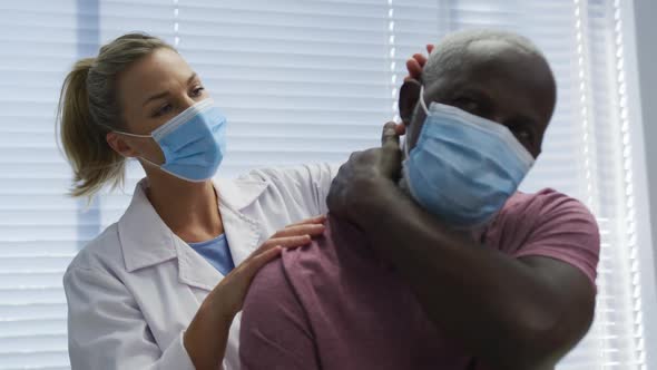 Diverse female orthopedic doctor examining male patient in face masks