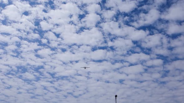 low angle view of single-engine airplane crossing the blue sky with fluffy clouds, over the city