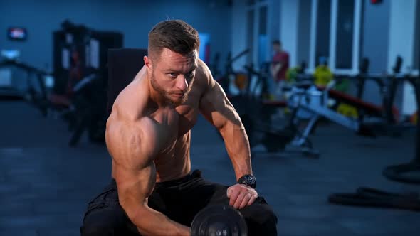 Handsome power athletic man bodybuilder doing exercises with dumbbell. 