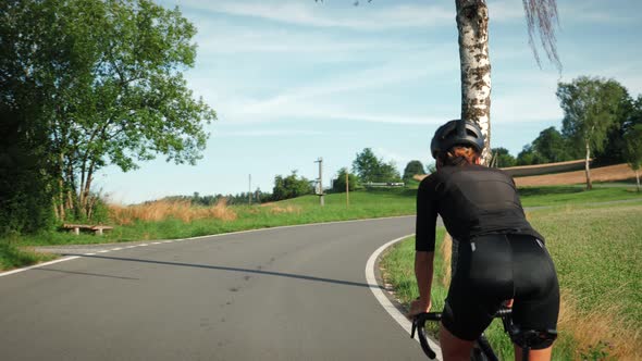 Road cyclist struggling during intense cycling training, pushing pedals uphill