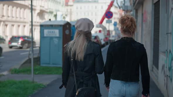 Mother And Daughter Walking Down An Urban Street In Prague