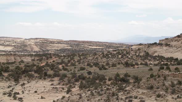 A wide panning shot of the Grand Staircase Escalante National Monument in Utah. In the distance a ro