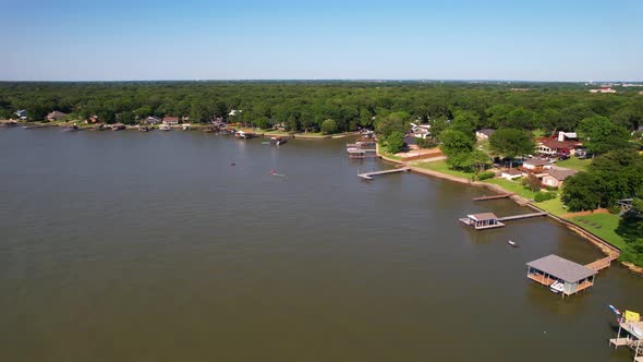 Aerial footage of Cedar Creek Lake in Texas. Drone flies over people in the water on watercrafts.