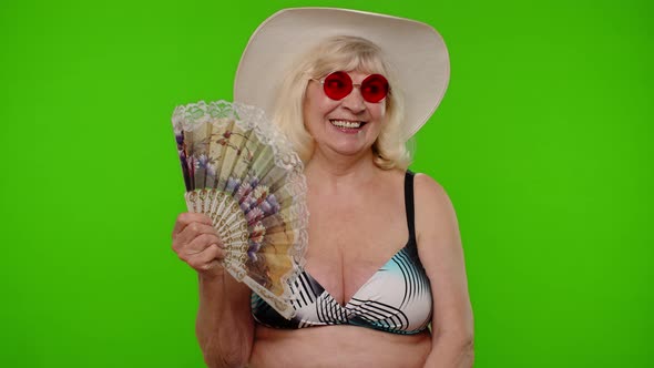 Elderly Woman Tourist in Swimsuit Bra Exhales From Heat or Stuffiness Waves Hand Fan at Herself