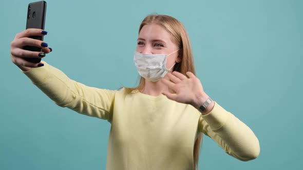 Young Girl with Medical Mask on Face Greets Friends During Online Conversation.