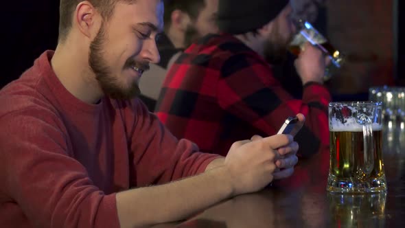 Guy Types on His Smartphone at the Pub