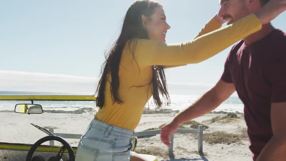 Happy caucasian couple hugging near beach buggy by the sea