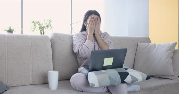 Focused Woman Working on Laptop at Home Sitting on Sofa