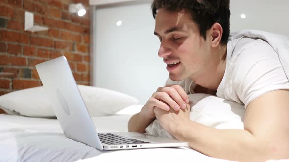 Online Video Chat on Laptop by Man Lying in Bed at Night