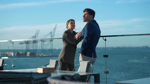 Financial Managers Discussing Project on Glass Balcony in Golden Sunlight