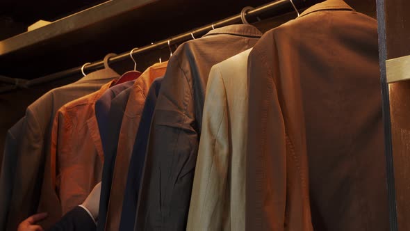 Closeup Man Chooses Suits on a Hanger in a Men's Clothing Store