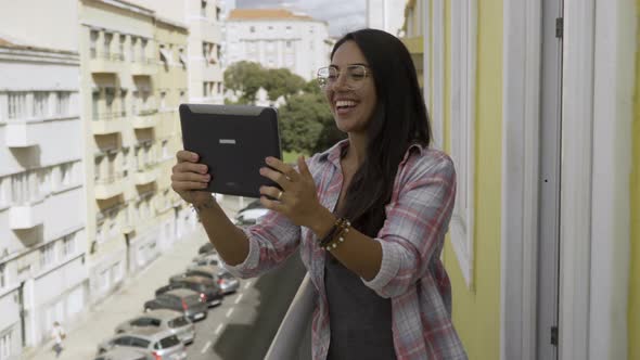 Smiling Hindu Woman Standing on Balcony and Talking Through Tablet