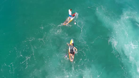 Aerial view of two men sup stand-up paddleboard surfing in Hawaii