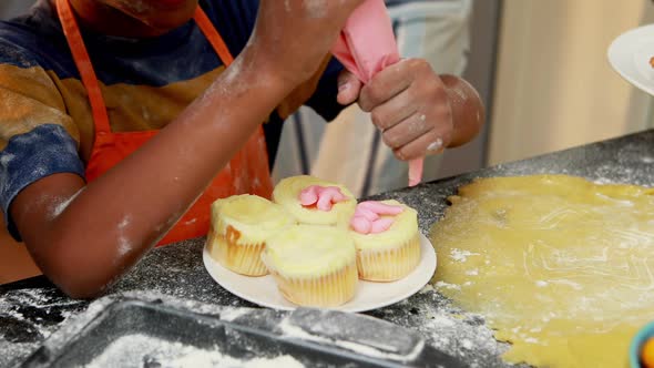 Mid section of boy preparing cupcake