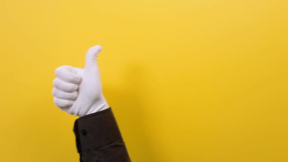A male's hand in a white glove shows a thumbs-up gesture. Yellow background.