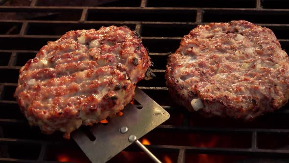 Two Delicious Meat Burger Cutlet with Onions Are Turned Around on the Grill