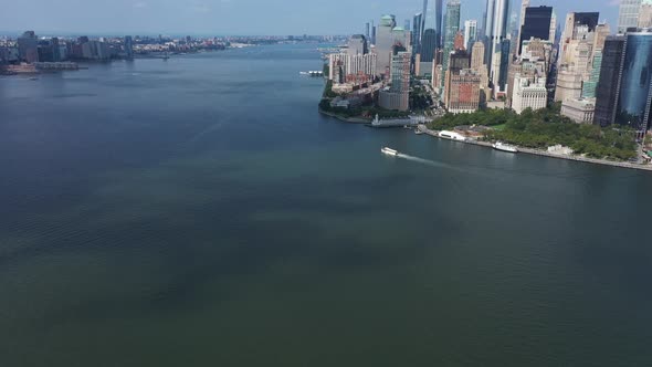 An aerial view of Upper Bay with a boat sailing by. The drone dolly in looking at lower Manhattan, t