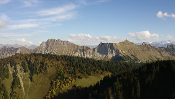 Aerial shot revealing alpine farm (Alpage) nested between to high hills with alpine landscape in the