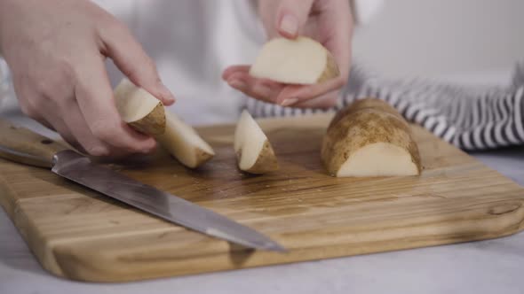 Step by step. Slicing russet potatoes in wedges with olive oil and spices to bake in the oven.