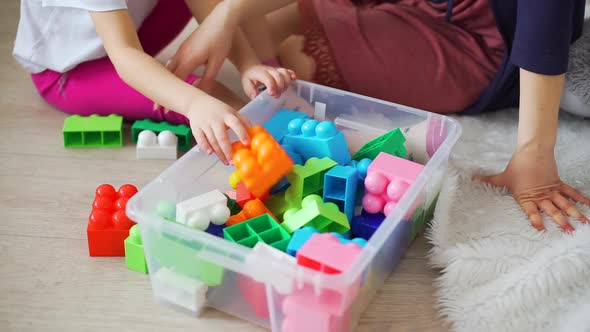 Little Girl with Mother Picking Up Toys Blocks