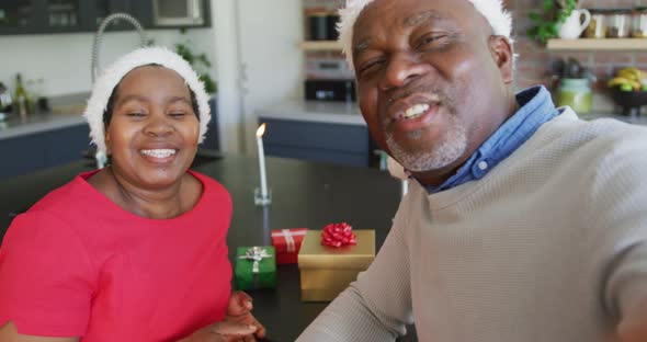 Happy african american senior couple in santa hats on video call at christmas time