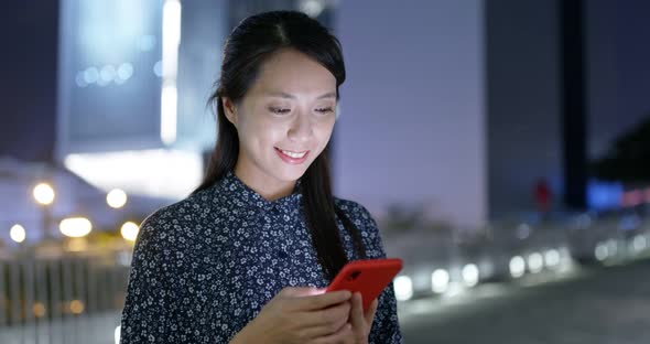 Woman look at mobile phone in city at night