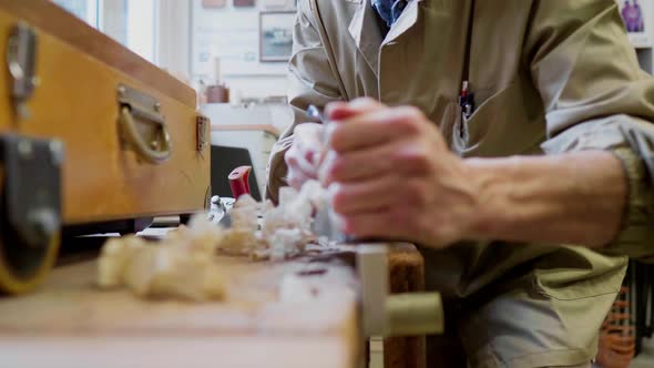 Woodworker planing wooden bar in workshop