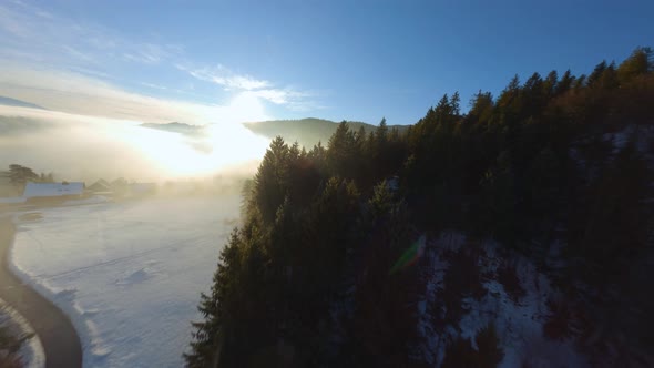 FPV Drone shot, the landscape covered under the fog with surrounding mountains in the morning at win