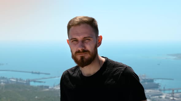 Confident Guy in Black T-shirt with Red Beard Looks at Camera. Video Portrait of Young Man in the