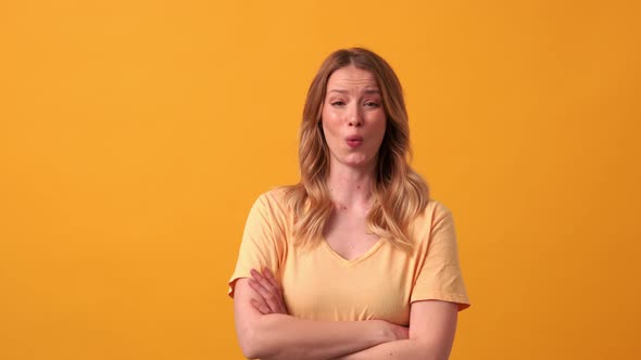 Angry blonde woman wearing yellow t-shirt saying what at the camera