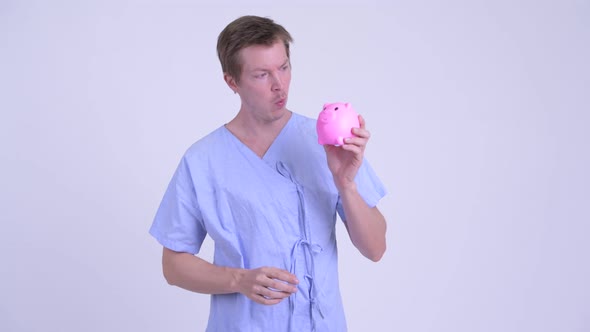 Happy Young Man Patient Holding Piggy Bank and Giving Thumbs Up
