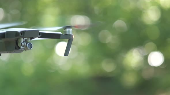 Drone aircraft with blurred fast rotating propellers and video camera flying in air.